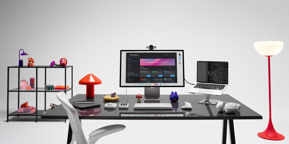 Modern open-office layout featuring dual-monitor workstations with Logitech webcams and headsets.